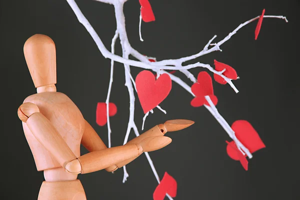 Wooden mannequin and decorative branch with hearts on gray background — Stock Photo, Image