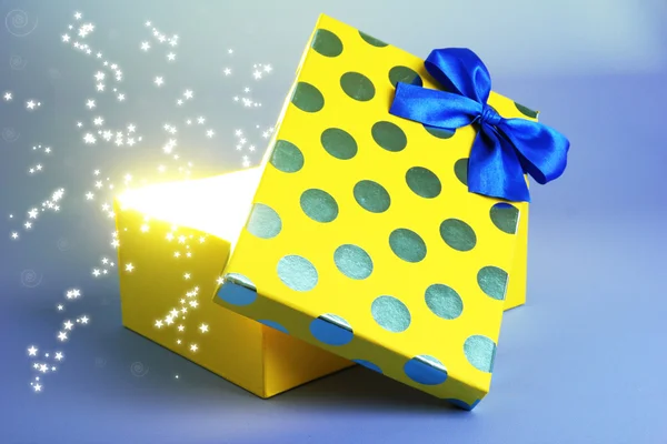 Caixa de presente com a luz brilhante sobre ele, sobre fundo azul — 스톡 사진