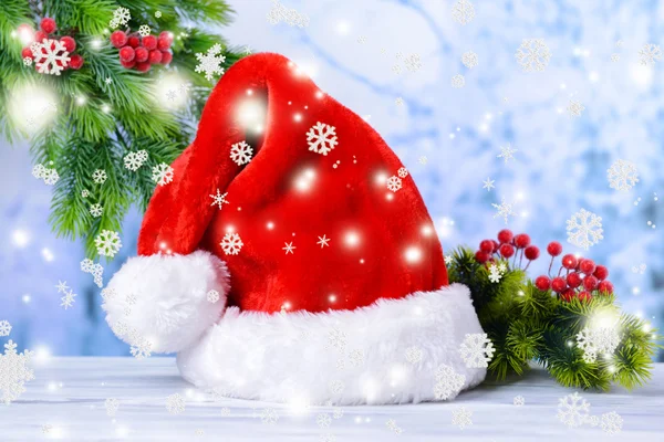 Состав с красной шляпой Санта-Клауса и рождественские украшения на светлом фоне — стоковое фото