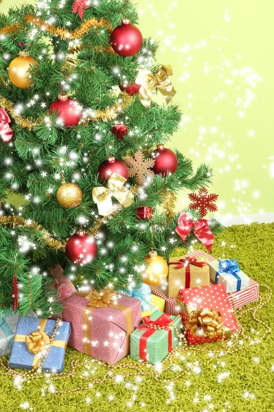 Dekorerad julgran med gåvor på grön vägg bakgrund — Stockfoto