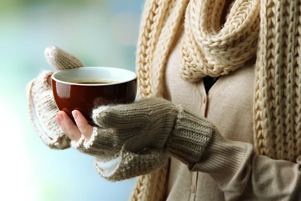 Mani femminili con bevanda calda, su sfondo chiaro — Foto Stock