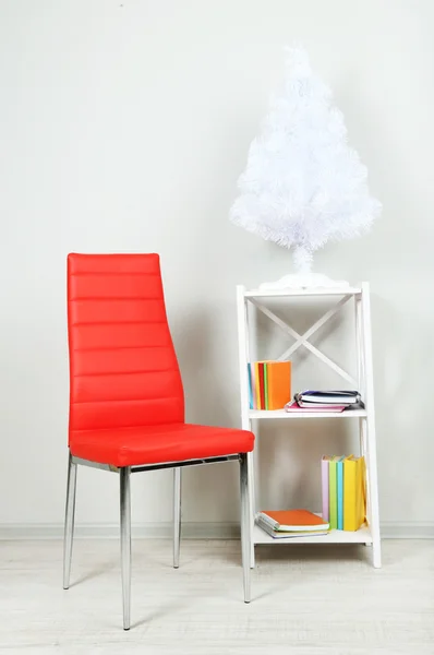Krásný interiér s moderní barevné židle, knihy o dřevěný stojan na zeď na pozadí — Stock fotografie