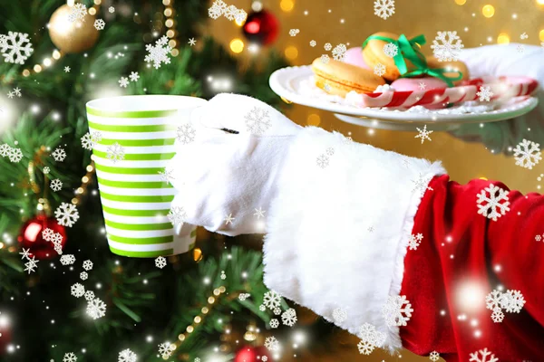Santa holding mug and plate with cookies in his hand, on bright background — Stock Photo, Image