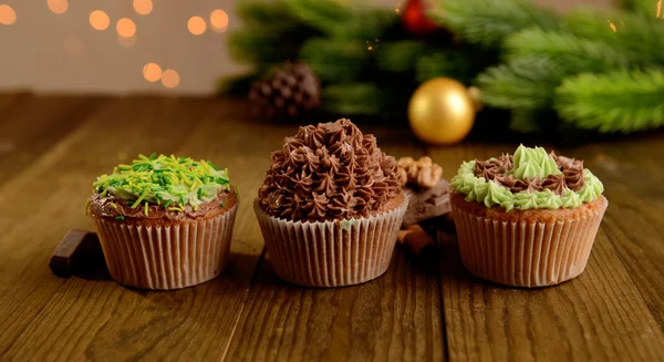 Cupcakes saborosos com creme de manteiga, na mesa de madeira, no fundo brilhante — Fotografia de Stock