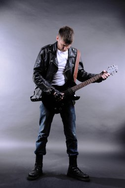 genç müzisyen gri arka plan üzerinde gitar çalmak