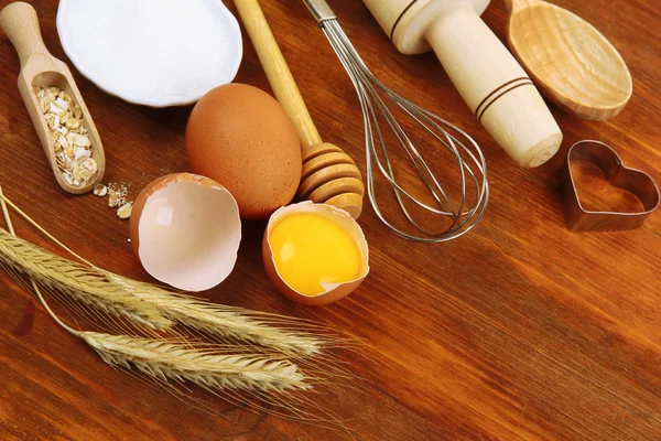 Vaření koncepce. základní pečící ingredience a kuchyňské nástroje na dřevěný stůl — Stock fotografie