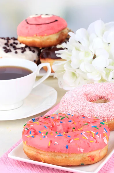 Sweet donuts with cup of tea on table on light background — Stock Photo, Image