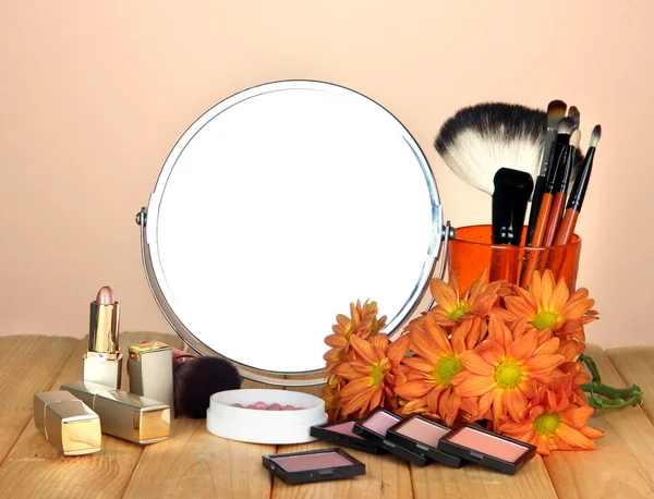 Round table mirror with cosmetics on table on beige background — Stock Photo, Image