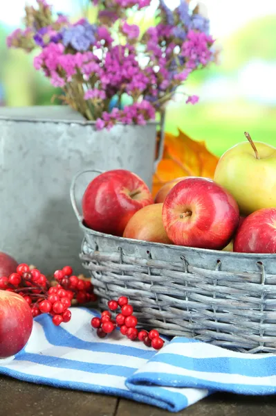 Ζουμερά μήλα στο καλάθι στο τραπέζι σε φυσικό φόντο — Φωτογραφία Αρχείου