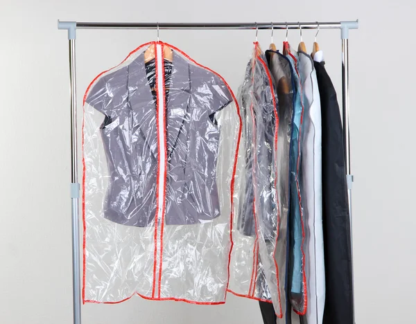 Office female clothes in cases for storing on hangers, on gray background — Stock Photo, Image