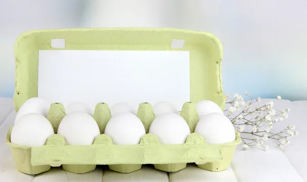 Uova in vassoio di carta su tavolo di legno su sfondo luminoso — Foto Stock