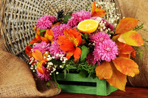 Flowers composition in crate on table on sackcloth background — Stock Photo, Image