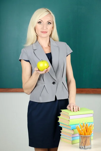 School teacher with apple on blackboard background