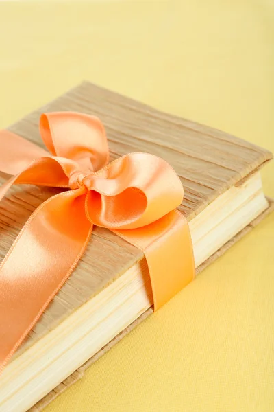 Book wrapped with color ribbon, on color background — Stock Photo, Image