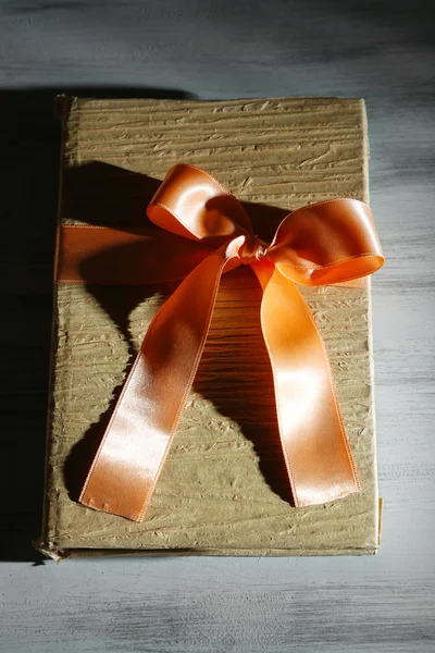 Βιβλίο, τυλιγμένο με χρώμα κορδέλα, σε ξύλινο φόντο χρώμα — Φωτογραφία Αρχείου