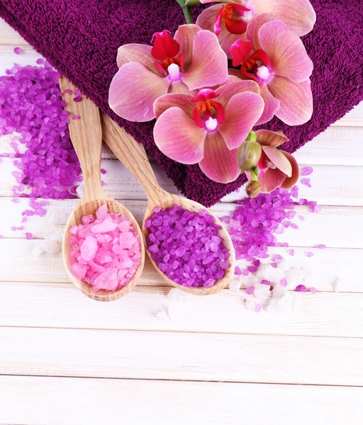 Nature morte avec belle fleur d'orchidée en fleurs et cuillères en bois avec du sel de mer, sur fond en bois de couleur — Photo