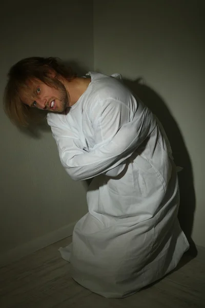 Mentally ill man in strait-jacket in room corner — Stock Photo, Image