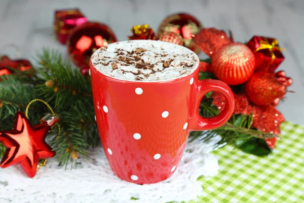 Hot chocolate with cream in color mug, on napkin, on Christmas decorations background — Stock Photo, Image