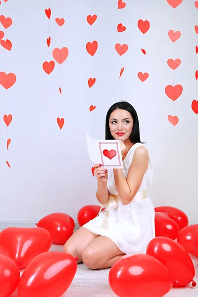 Jovem atraente ler cartão no quarto decorado no Dia dos Namorados — Fotografia de Stock