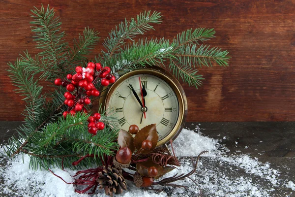 Clock with fir branches and Christmas decorations on table on wooden background — Stock Photo, Image