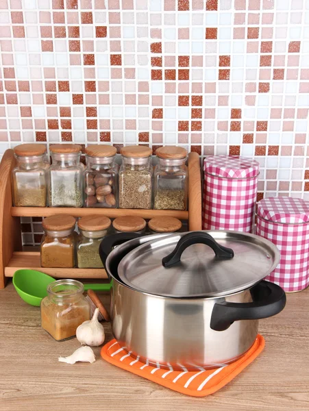 Pote e especiarias na cozinha na mesa em azulejos mosaico fundo — Fotografia de Stock