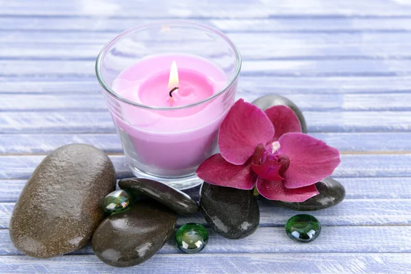 Prachtige kleurrijke kaarsen en orchideebloem, op een houten achtergrond kleur — Stockfoto