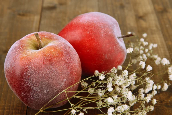 Red frosted apples with flowers on wooden background — Stock Photo, Image