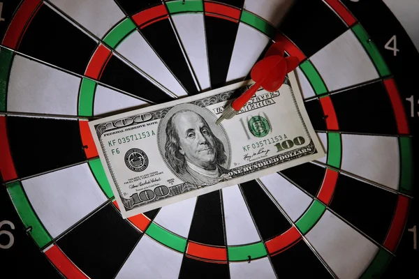 Money pierced by arrow on dartboard close up — Stock Photo, Image