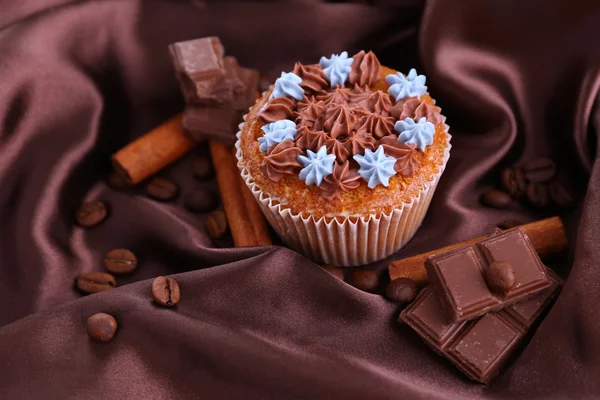 Välsmakande cupcake med smörkräm, på färg tyg bakgrund — Stockfoto