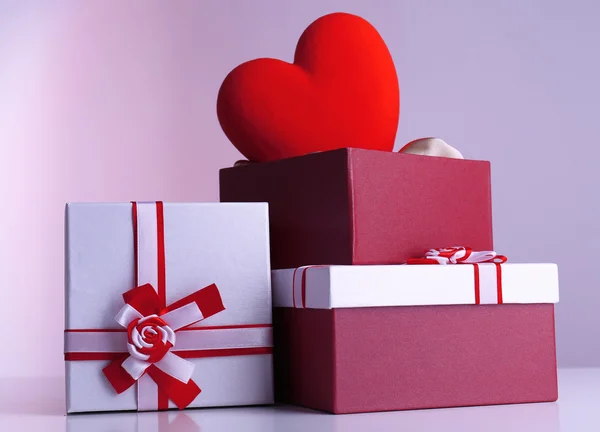 Pile de boîtes-cadeaux et coeur décoratif, sur fond de couleur — Photo