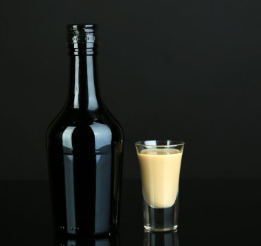 Baileys liqueur in bottle and glass isolated on black clipart