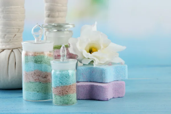Aromatické soli ve skleněných lahvích a bylinné komprimovat koule pro lázeňské léčby, na modrém pozadí — Stock fotografie