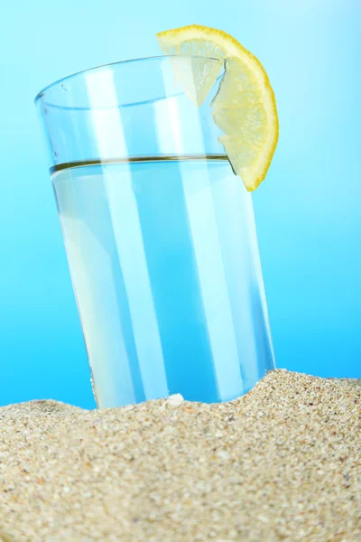 Beach cocktail in sand on blue background — Stock Photo, Image