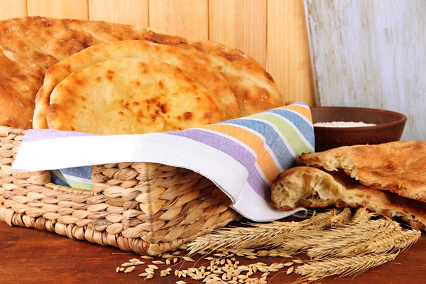 Pães Pita em cesta com picos e farinha na mesa sobre fundo de madeira — Fotografia de Stock