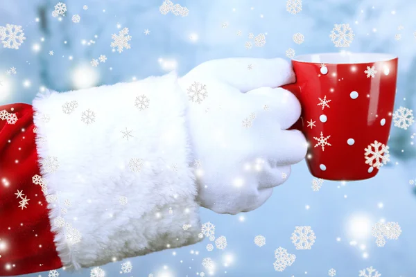 Santa bedrijf mok in zijn hand, op lichte achtergrond — Stockfoto