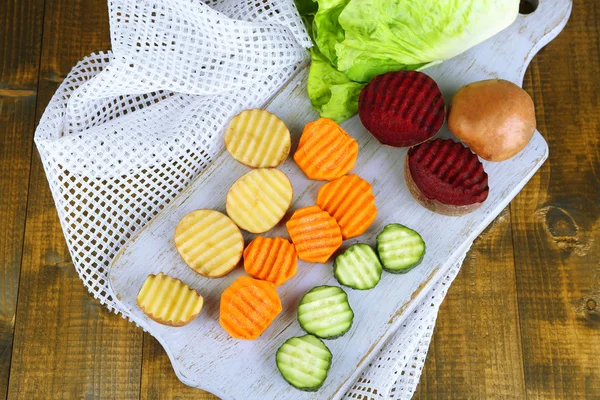 Renkli arka plan üzerinde kesme tahtası üzerinde güzel dilimlenmiş sebze — Stok fotoğraf