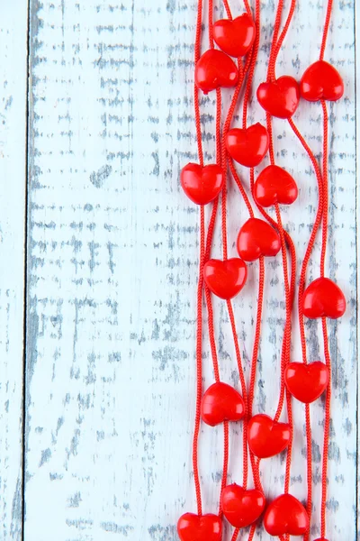 Heart-shaped beads on string on wooden background — Stock Photo, Image