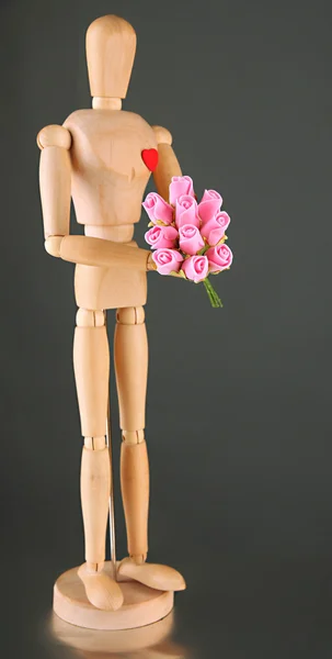 Wooden mannequin holding bouquet on gray background — Stock Photo, Image