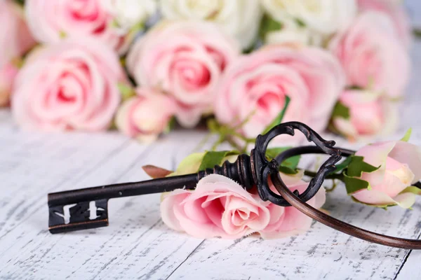 Llave de la felicidad. Foto conceptual. Llave con rosas, sobre fondo de madera claro —  Fotos de Stock