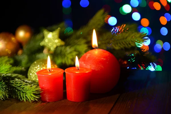 Composition with burning candles, fir tree and Christmas decorations on multicolor lights background — Stock Photo, Image