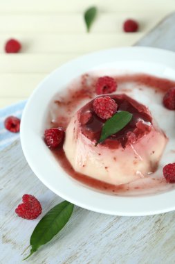 Panna cotta ahşap zemin üzerinde frambuaz sos ile