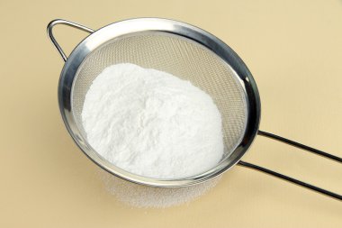 bej renkli arka plan üzerinde metal elek pudra şekeri