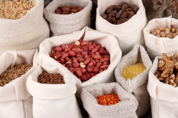 Různé druhy fazolí v pytlích na dřevěné pozadí — Stock fotografie