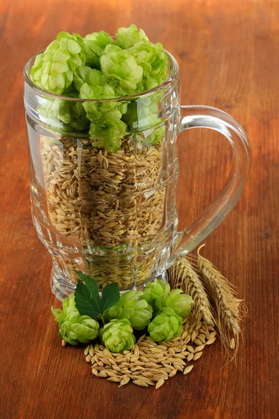 新鲜绿色的啤酒花和大麦，木制背景上玻璃 — 图库照片