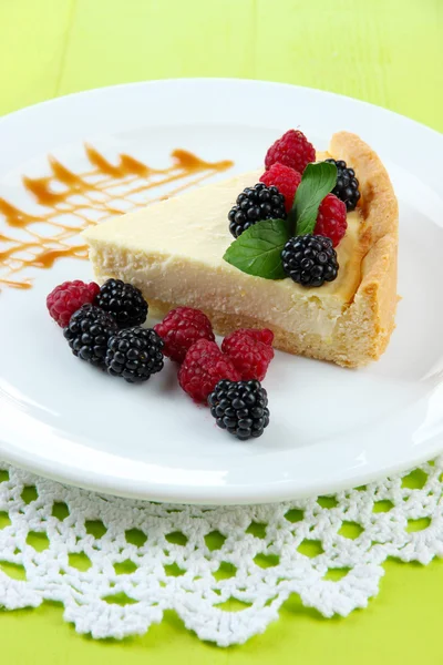 Fatia de cheesecake com framboesa e amora-preta no prato, no fundo de madeira — Fotografia de Stock