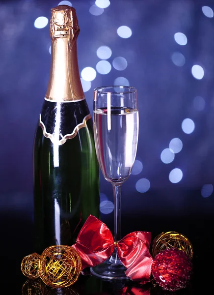 Bouteille de champagne avec verre et boules de Noël sur fond de lumières de Noël — Photo