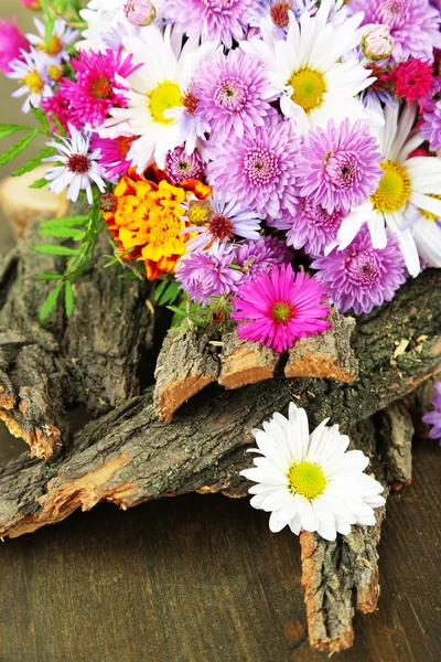 Flores silvestres y corteza de árbol en mesa de madera —  Fotos de Stock