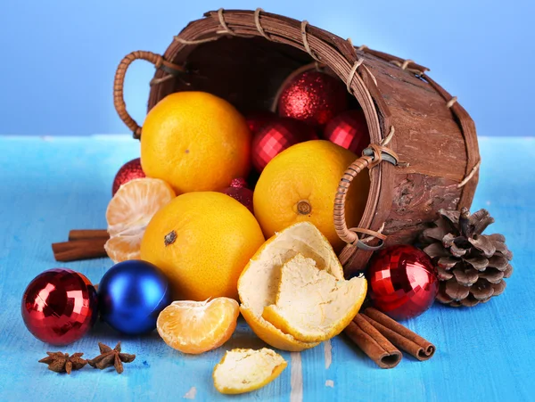 Mandarinas navideñas y juguetes navideños en cesta sobre fondo azul — Foto de Stock