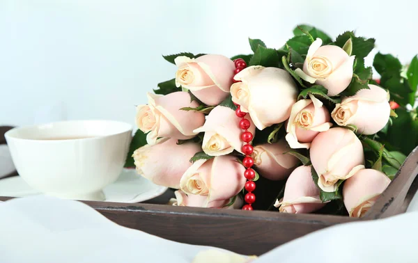 Beautiful bouquet of roses, on wooden tray, on light background — Stock Photo, Image