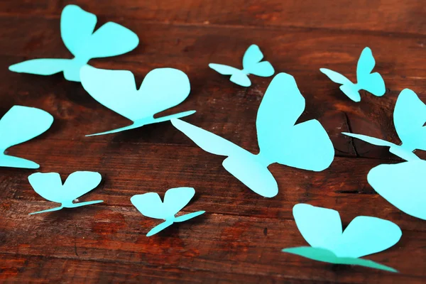 Papel azul mariposas sobre fondo tablero de madera — Foto de Stock